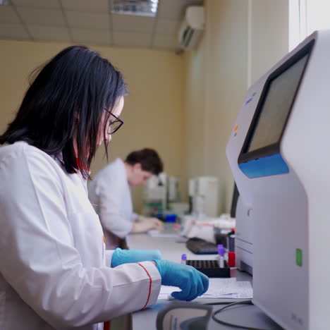specialist with blood samples in the laboratory. female technician in medical uniform working at modern machine in the research laboratory.