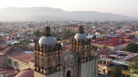 aerial view, domes, towers and facade of santo domingo de guzman church, oaxaca city mexico, landmark of historic colonial downtown, parallax drone shot