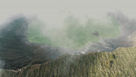 Beautiful-aerial-drone-shot-of-white-clouds-passing-over-the-crater-and-lake-of-El-Chichonal-volcano-in-Chiapas,-Mexico-on-a-cloudy-day