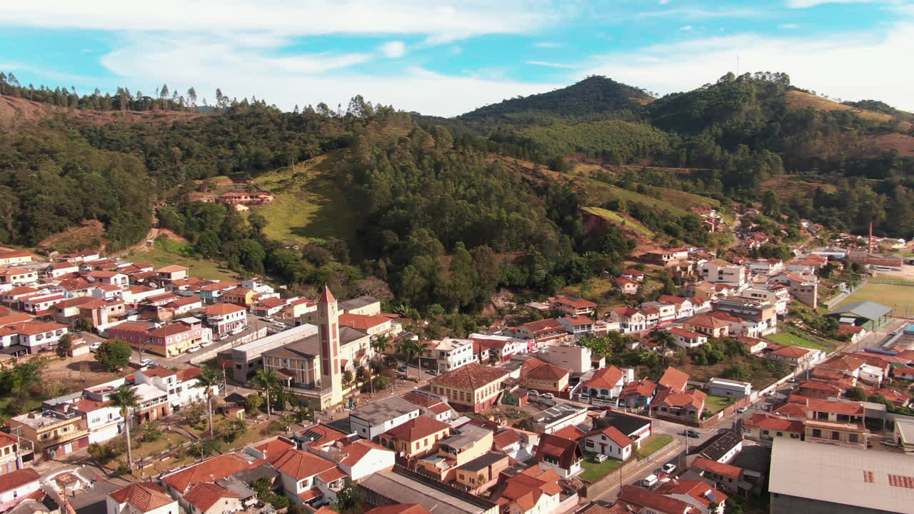 Aerial view of Delfim Moreira in Minas Gerais, Brazil, featuring a small town with clustered houses surrounded by hills and forests