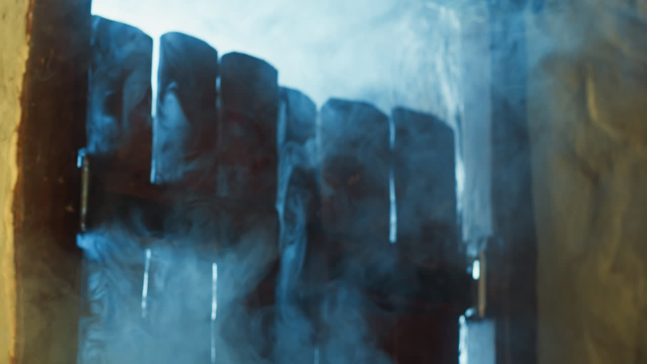 flujos de aire frío rizado se filtran a través de la puerta de tabla vieja de la taberna. niebla misteriosa flota dentro del pub medieval en el crepúsculo de invierno. escena hechizada de la difusión de la niebla. cámara manejada