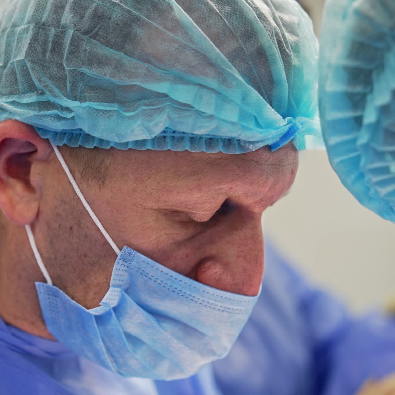 Aged male experienced surgeon working in a team of doctors. Portrait of calm confident professional performing his job. Close up