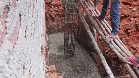concrete pouring around rebar cage for column footing at construction site. day time, stable shot, top down shot, 4k