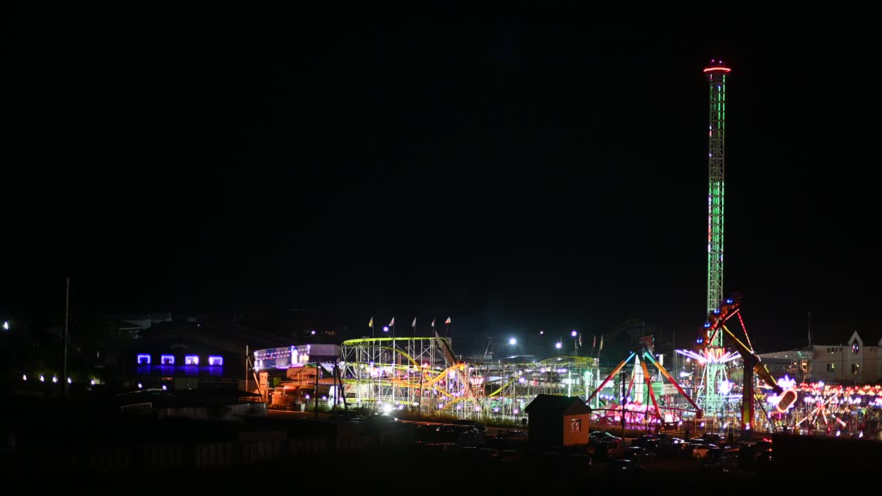 vista nocturna del parque de atracciones, la rueda de la ferris y otras formas de entretenimiento