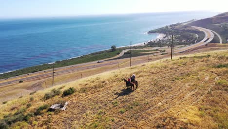 Hermosa-Antena-De-Jubilación-Pareja-De-Jubilados-A-Caballo-En-Un-Rancho-Con-Vistas-Al-Océano-Pacífico-En-Santa-Bárbara,-California-2