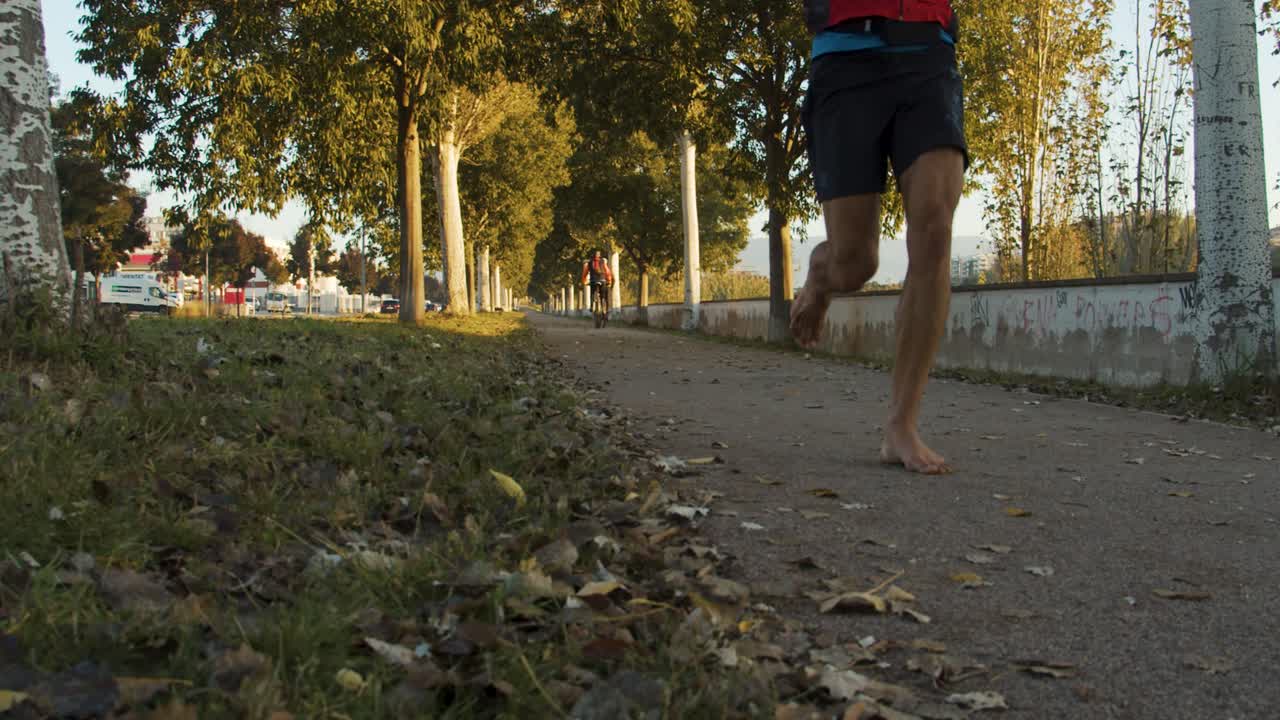 달리기 선수 는 가을 이 왔기 때문 에 많은 잎 이 떨어지는 나무 들 이 둘러싸인 돌길 에서 맨발 로 달린다
