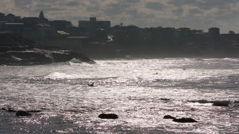 waves crash with people swimming at sunrise early in the morning, manly beach sydney australia