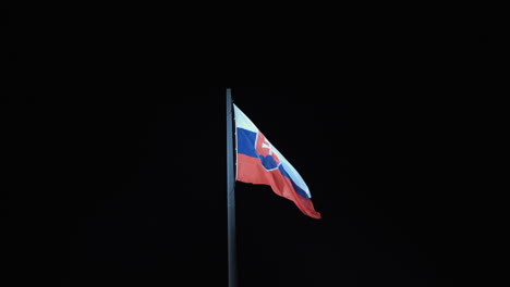 Slovakia-Flag-on-a-pole-blowing-in-a-wind-at-Night,-black-background-4k