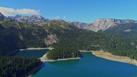 Vista-Aérea-De-Lagos-Entre-Las-Montañas-Rodeadas-De-Bosques-De-Pinos-Y-Hermoso-Cielo-Azul-Con-Nubes