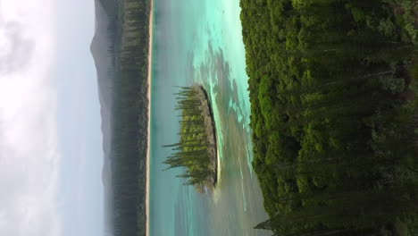 aerial-ascending-shot-revealing-columnar-pines,-crystal-water-and-N'Ga-peak,-Isle-of-pines