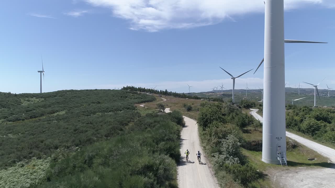 dos ciclistas en la carretera con molinos de viento