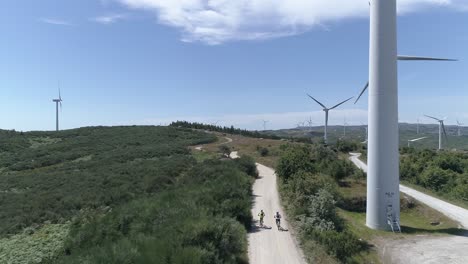 two cyclists on the road with windmills