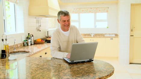 hombre usando una computadora portátil en la cocina