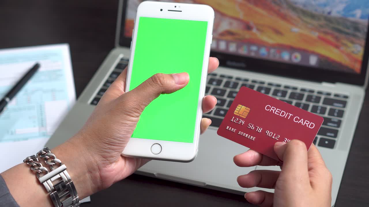 여성은 신용카드로 휴대 전화로 쇼핑을 하고, 신용카드를 손에 고 초록색 화면을 가지고 있습니다.