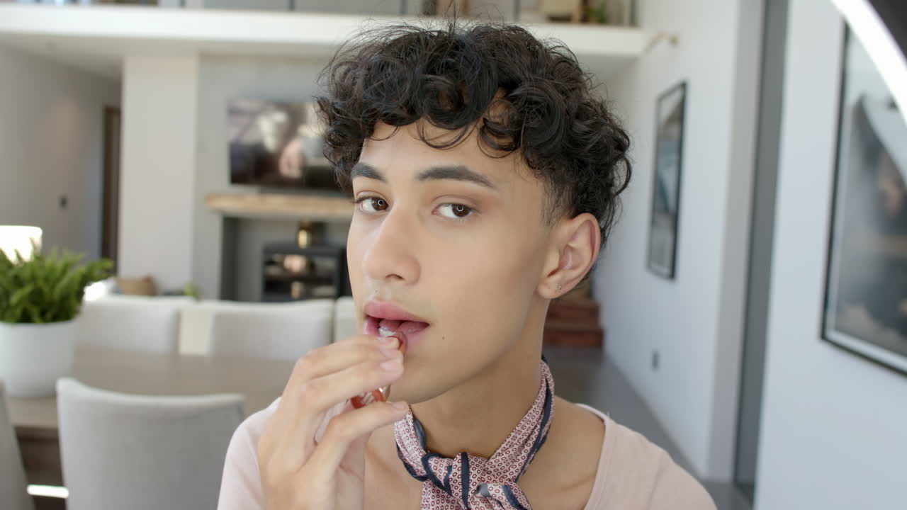 Applying lip balm, young person with curly hair in modern home setting
