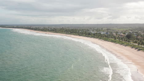 Vista-Aérea-De-La-Playa,-Gran-Zona-Verde-Con-Palmeras-Y-Algunas-Personas-Caminando,-Guarajuba,-Bahía,-Brasil