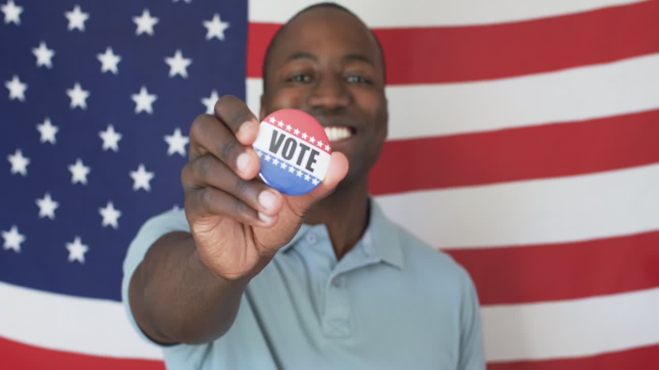 un joven afroamericano muestra con orgullo una insignia de votante