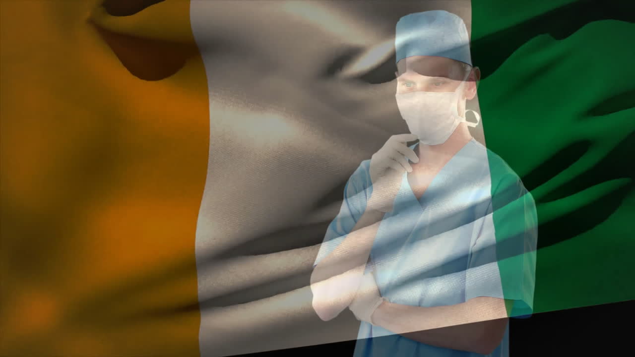 Healthcare professional wearing scrubs and mask standing against Irish flag animation