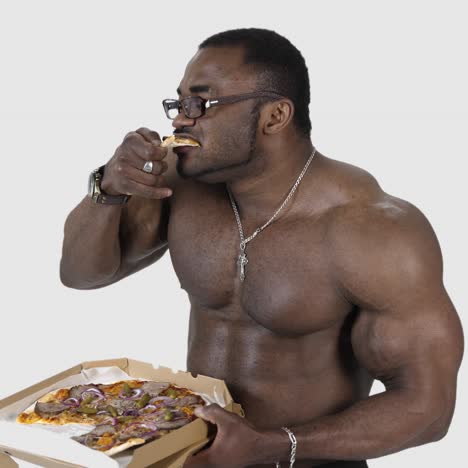african male eating pizza. fit young african man with beautiful torso eating pizza