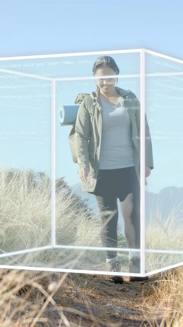 Vertical video: Woman hiker walking toward frame, causing code cube to wrap torso for tech demo