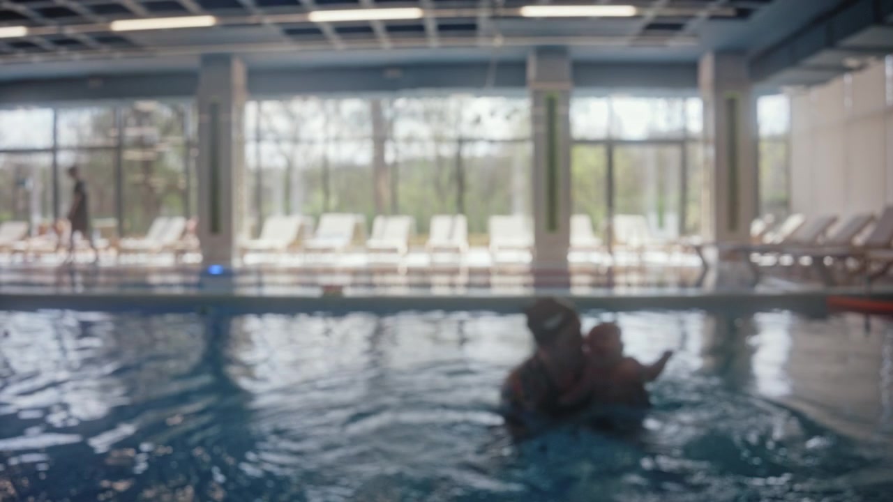 Blurred view of children swimming assisted by instructors during swimming lessons