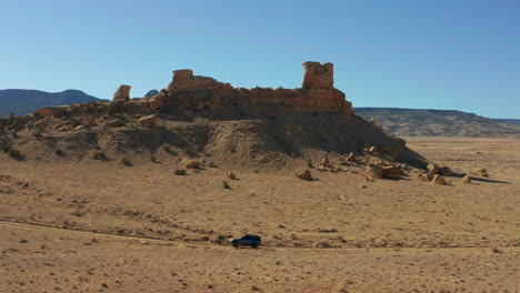 car races down desert dirt road in southwest near rock formation, 4k