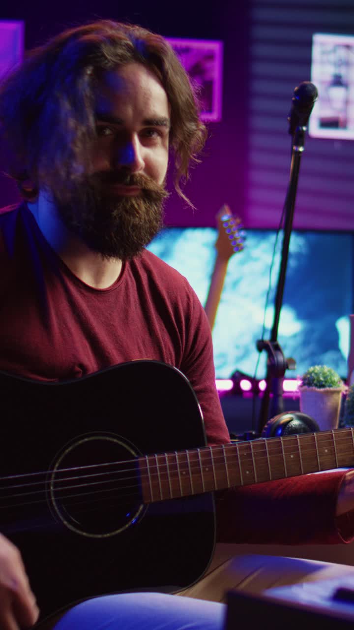 Mand der spiller akustisk guitar i musikstudie derhjemme med neonbelysning