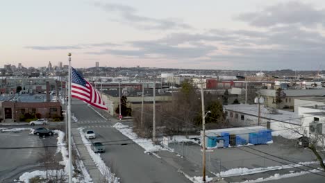 flag of the united states of america flying over an urban area - aerial view in slow motion