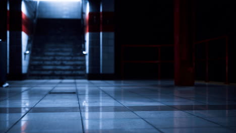 dark underground passageway with shiny tiles and illuminated stairs ahead