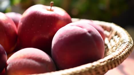 a close-up view of freshly harvested red apples and peaches displayed in a woven basket, highlighting their vibrant color and natural texture