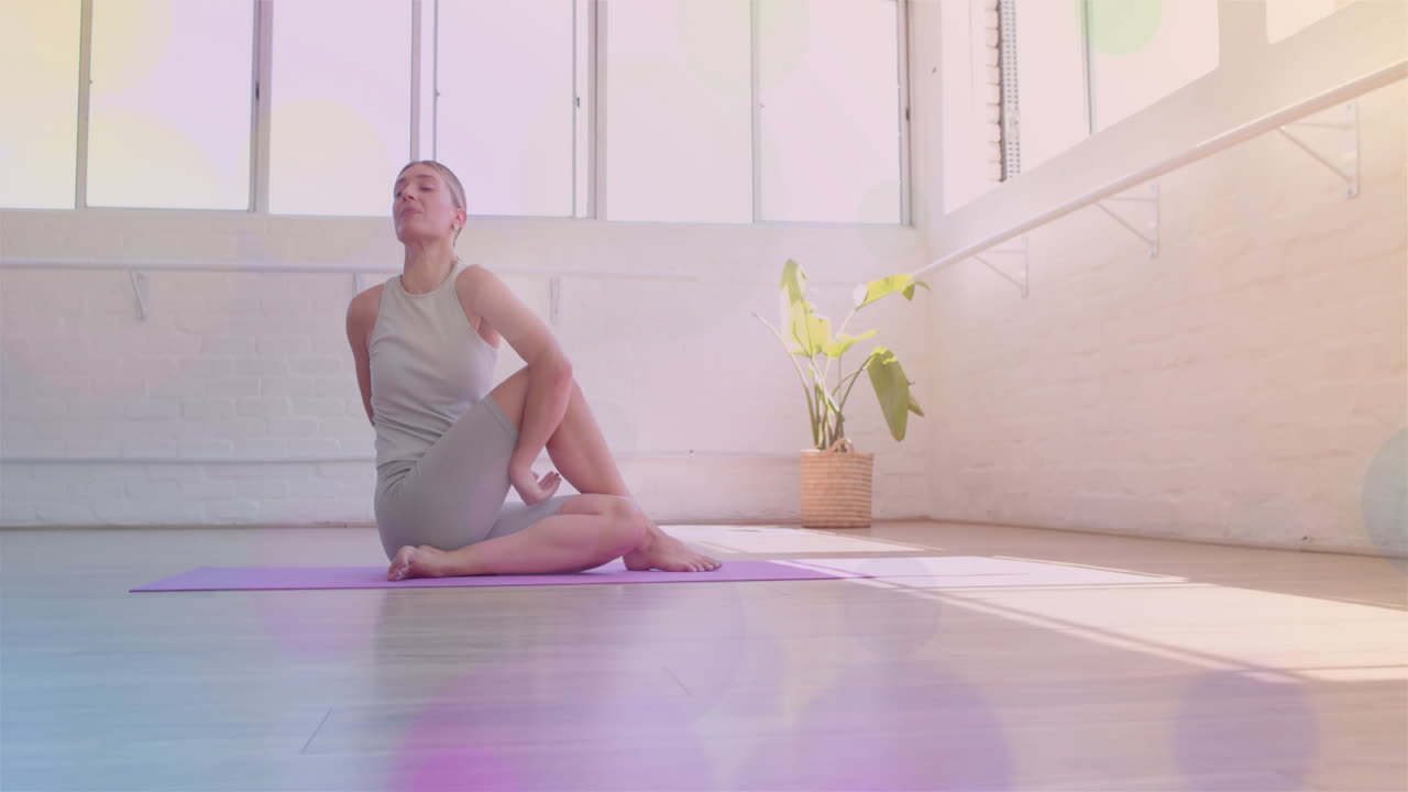 Mulher praticando yoga no tapete em um estúdio iluminado com animação de bokeh colorido