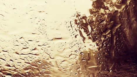 Low-visibility-for-raindrops-over-windscreen-while-driving-on-highway-with-trees-in-background-and-wiper-removing-rain-for-bad-weather