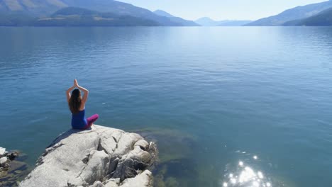 mujer realizando yoga en la orilla del lago 4k