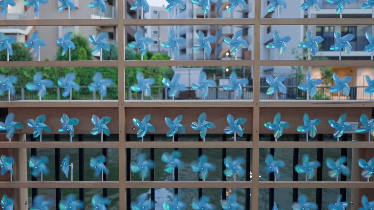 A shot capturing blue pinwheels decorating the railing of the promenade at Tokyo Mizumachi along the Kita-jūkken-gawa River at dusk