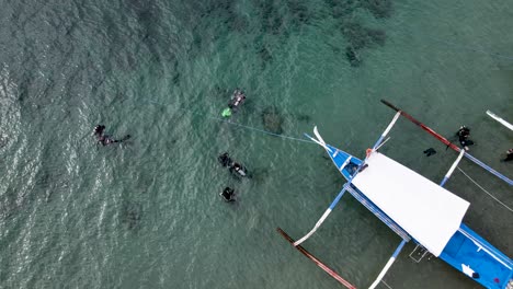 Scuba-Divers-Beside-a-Boat-Aerial-Drone-Top-Shot-4k