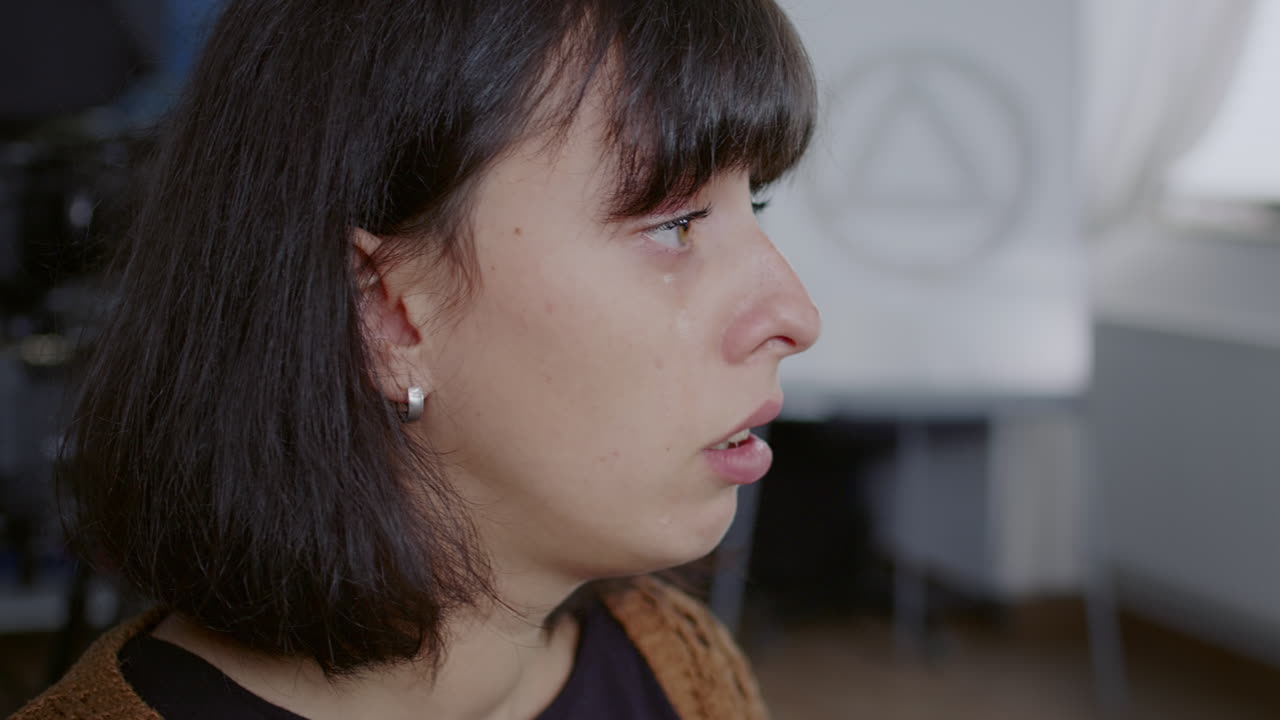 Close up of woman listening to story about addiction and crying at aa group meeting