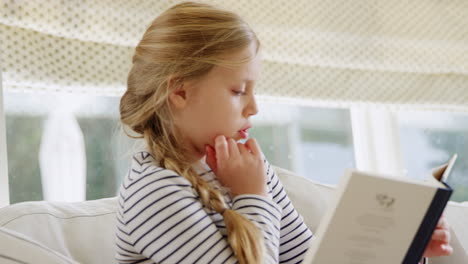 Niña-Relajándose-En-El-Sofá-En-Casa-Leyendo-Un-Libro