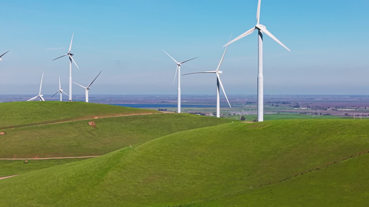 Erhöhte Perspektiven zeigen das Ausmaß der Windparks nahe dem Altamont Pass, mit langen Reihen von Turbinen, die sich in rhythmischer Bewegung über das Gelände ziehen. Aufsteigende Drohnenaufnahme in 4K.