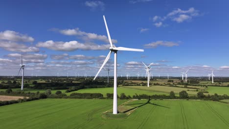 wind turbines farming wind energy, green fields, blue sky, countryside, sunny, slow drone orbit, slow shutter speed