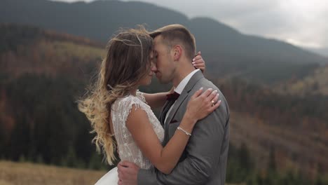 Lovely-young-newlyweds-bride-and-groom-embracing,-hugging-on-mountain-slope,-wedding-couple-in-love