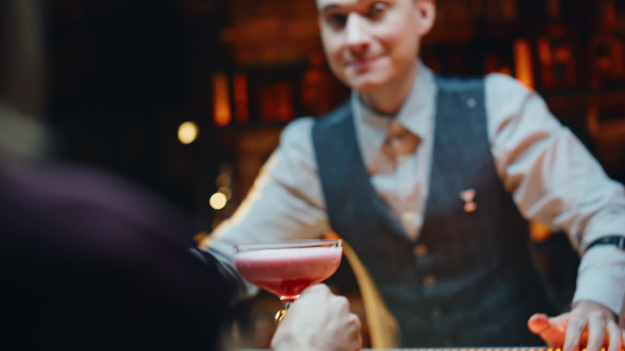 Barman allegro che appoggia dei cocktail sul bancone all'interno. Barista che serve bevande