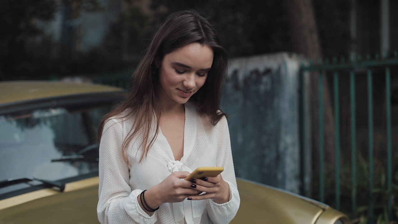 Woman with phone next to a car