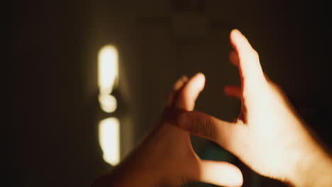 pov shadow play on wall with hands under sunbeam, creating figures with a hand-held camera