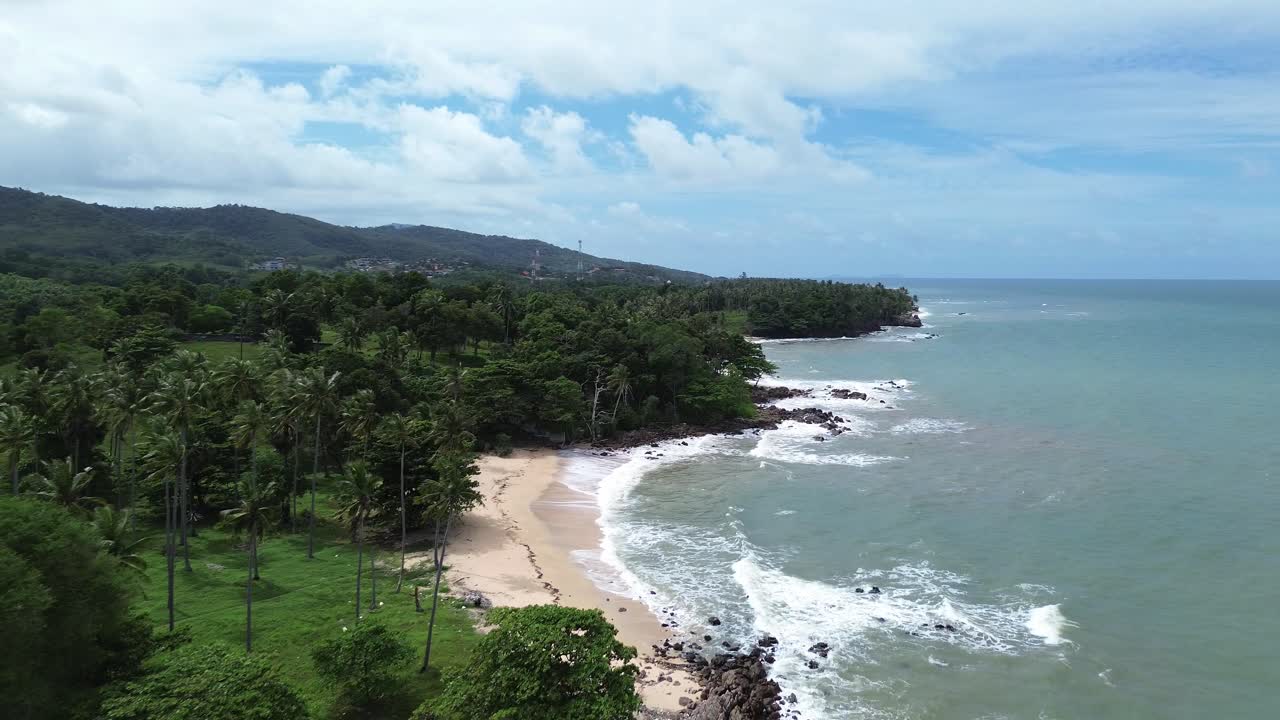 Drone footage showing lush green palm trees, tropical forest and rocky coastline with hidden sandy beaches on Koh Lanta island, Thailand, overlooking the turquoise Andaman Sea