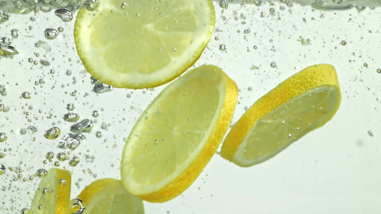 Primo piano di fette di limone fresche che galleggiano in acqua effervescente