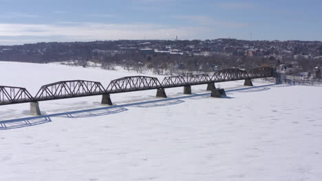 aerial: moving forward over walking bridge in fredericton on sunny winter day