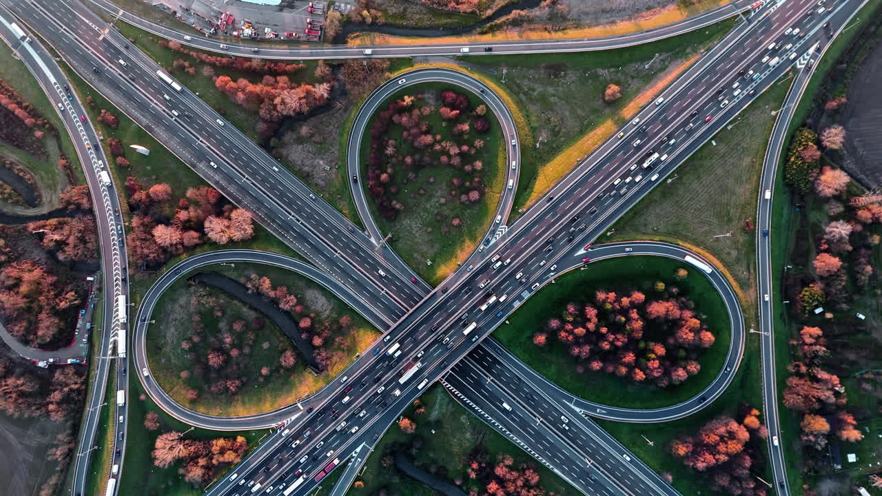 Aerial view of busy highway interchange at autumn sunset, lush landscape