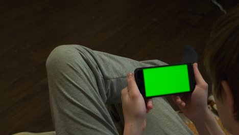 person using a smartphone with a green screen