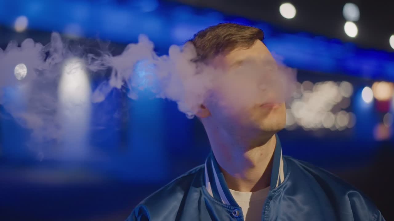 hombre blanco vapeando bajo las luces de neón de un puente, un viajero nocturno haciendo una pausa para inhalar, primer plano de perfil con bokeh azul, columna de humo deslizándose por la cara, chaqueta bomber, ambiente cinematográfico de soledad, vacío