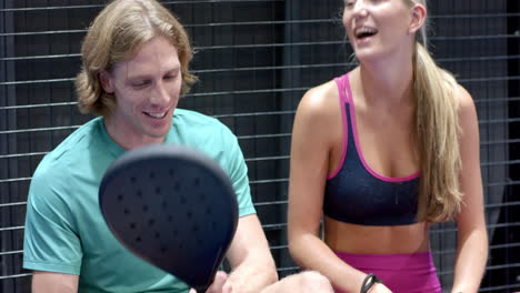 two people in sportswear chatting happily after padel tennis match indoors, at indoor court